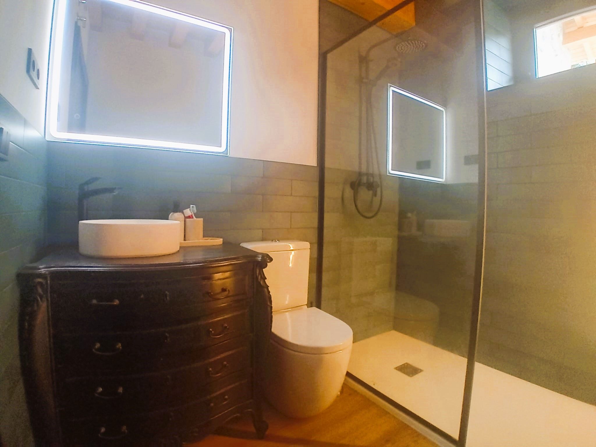 Un baño con tocador negro, lavabo blanco y retrete.