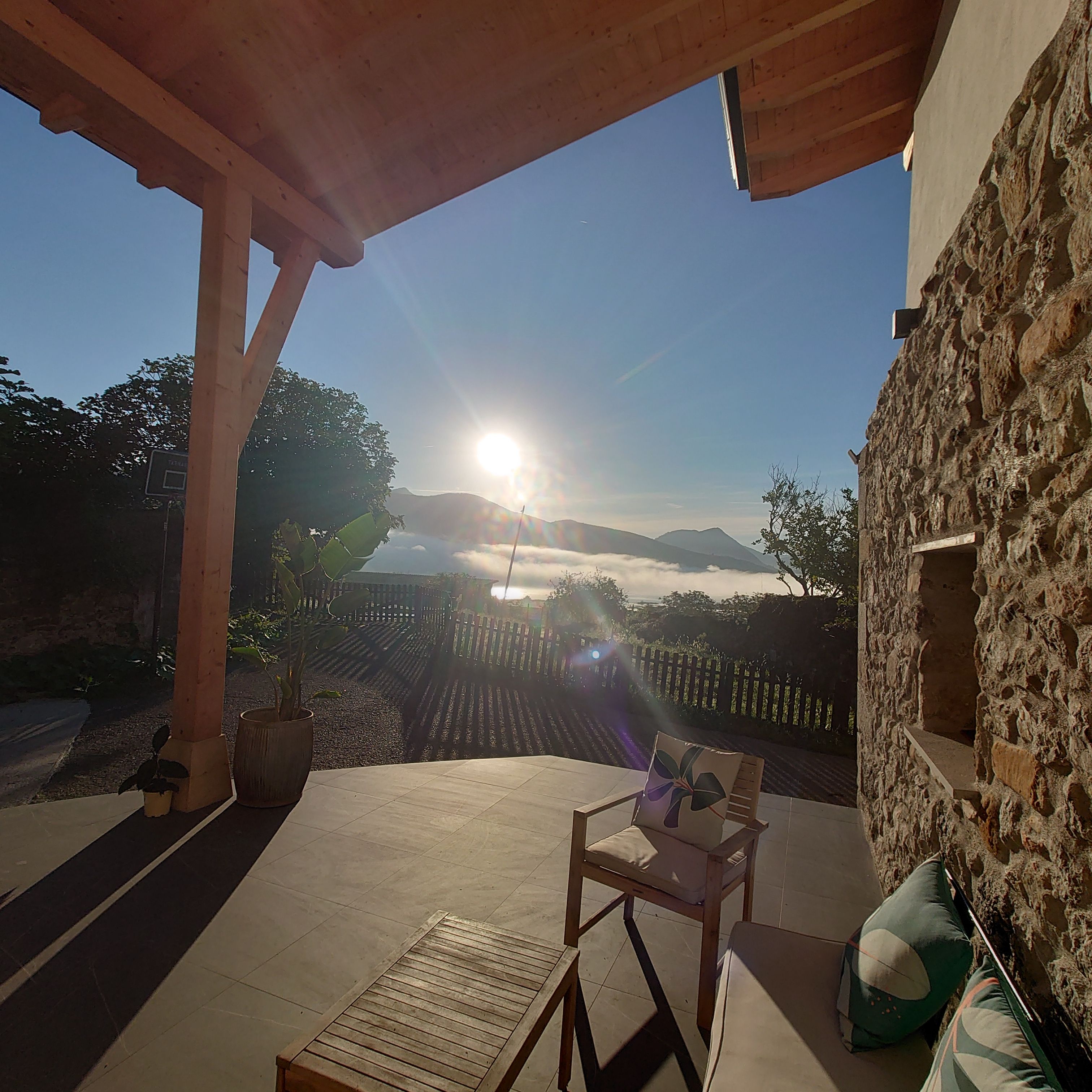 Un espacio de estar al aire libre con vistas a montañas y al sol poniéndose en el horizonte.