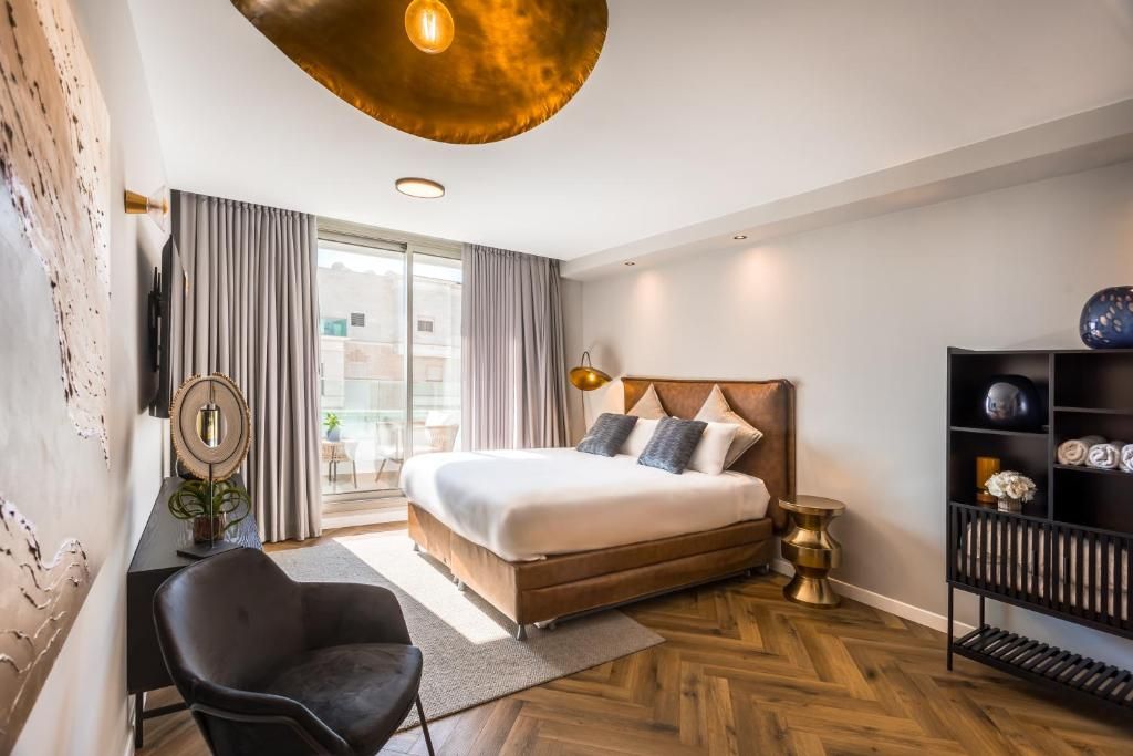 Una habitación de hotel moderna con una cama grande, un escritorio, una silla y una estantería.