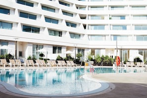 Uma área de piscina de hotel com espreguiçadeiras e guarda-sóis.