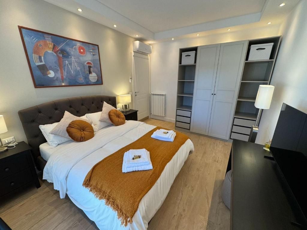 A hotel room with a bed, nightstands, a desk, a television, a wardrobe, and a painting on the wall.