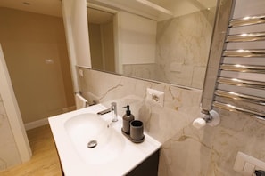 Ein modernes Badezimmer mit Marmorwaschbecken, Chromarmaturen und einem Handtuchhalter.