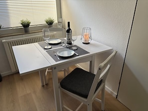 A dining table set with plates, cutlery, and a bottle, with a chair in front. - New Listing (Winterberg)