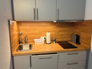 A compact kitchen with a wooden countertop, a stainless steel sink, a kettle, a kettle holder, and a coffee machine. - New Listing (Winterberg)