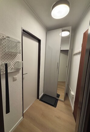 A narrow hallway with a door, a small shelf unit, and a mirror reflecting the room. - New Listing (Winterberg)