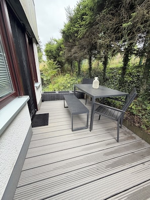 An outdoor patio with a table and benches, surrounded by greenery and a fence. - New Listing (Winterberg)