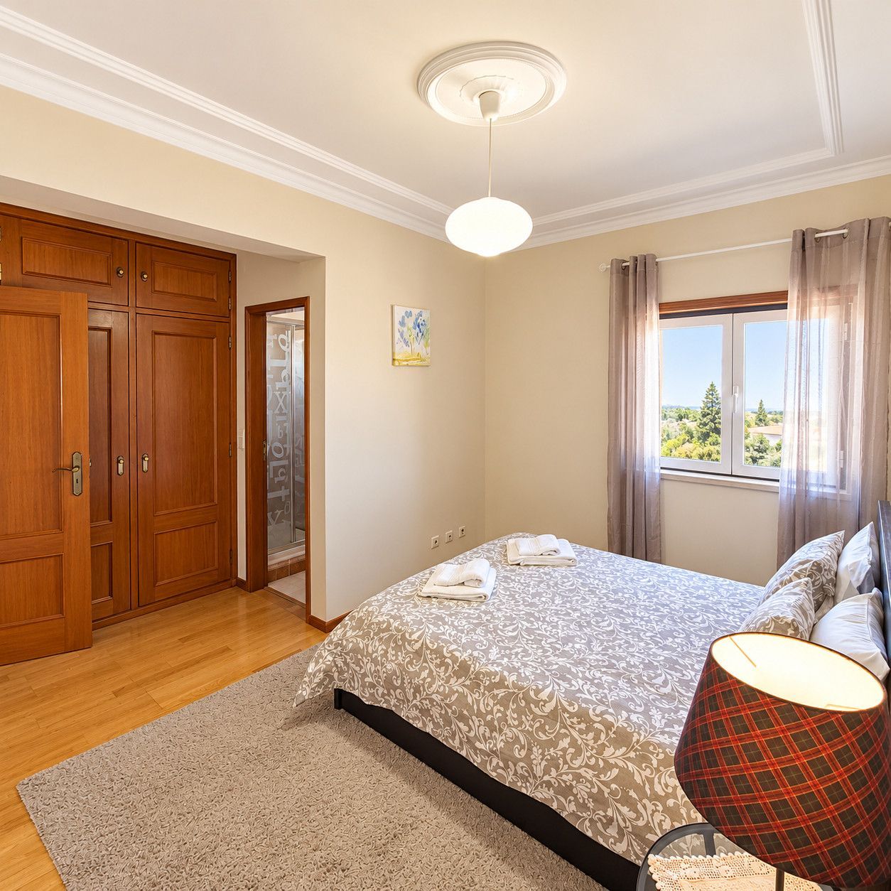 Une chambre à coucher comprenant un lit, une table de chevet, une lampe, une fenêtre avec des rideaux et une porte donnant sur une autre pièce.