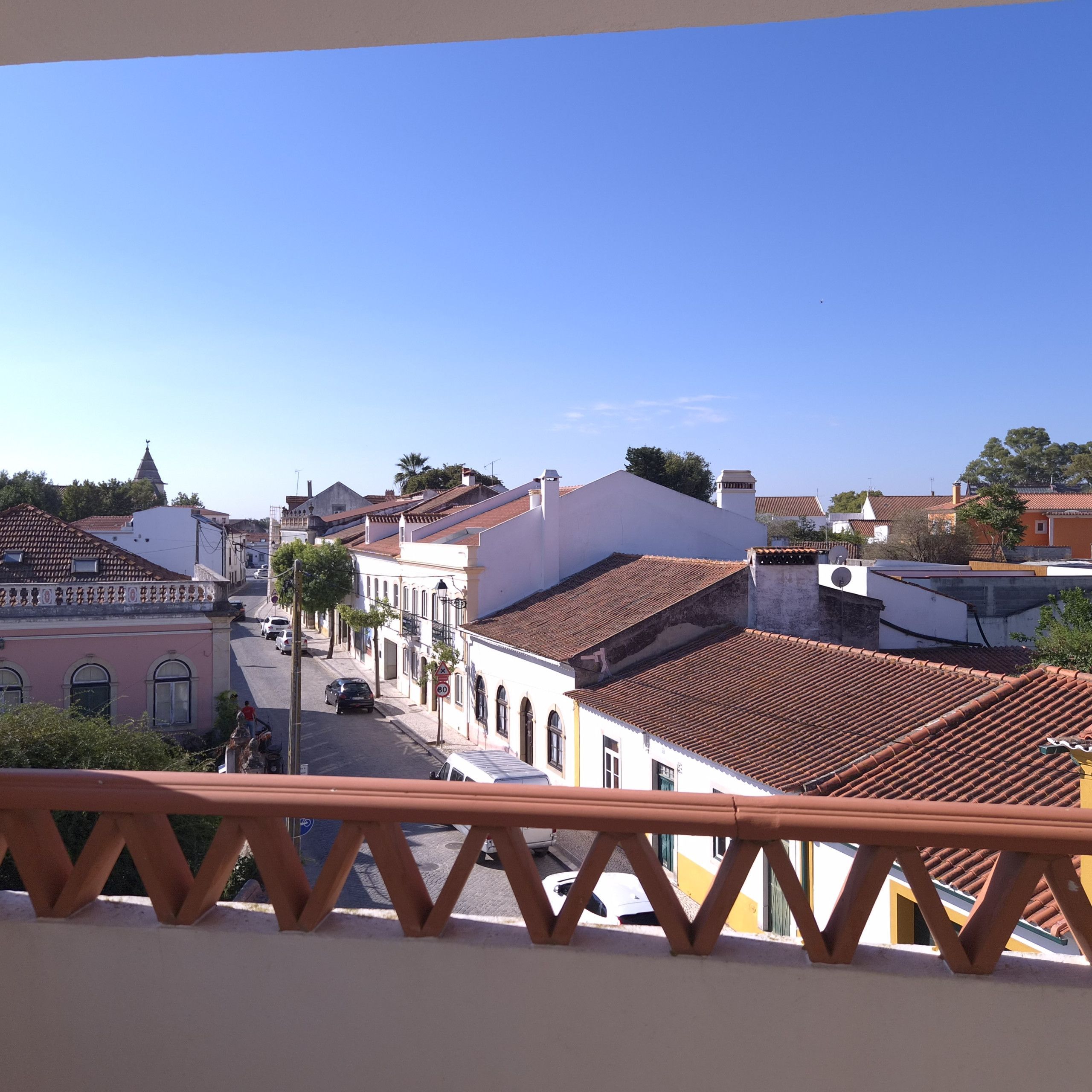 En balkon med udsigt over en gade med bygninger, heriblandt en kirke med et tårn.