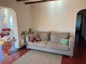 Ein Wohnzimmer mit einer Couch, einem Sessel, einem kleinen Tisch und einem dekorativen Regal.