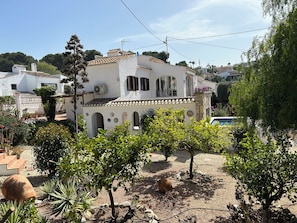 A white building with a tiled roof, surrounded by greenery and a pool. - New Listing (El Tosalet)