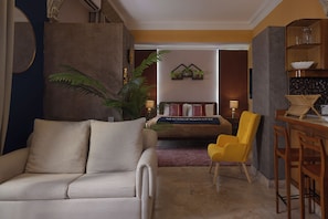 A living room with a sofa, a yellow armchair, a coffee table, and a dining area with a bar. - Loft moderno para 2 personas | Plaza Bolívar, Casco Viejo. (Casco Viejo)