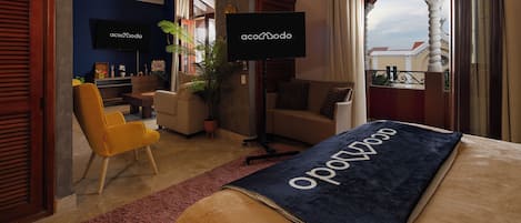 A hotel room with a bed, a sofa, a chair, a TV, and a balcony with a view.