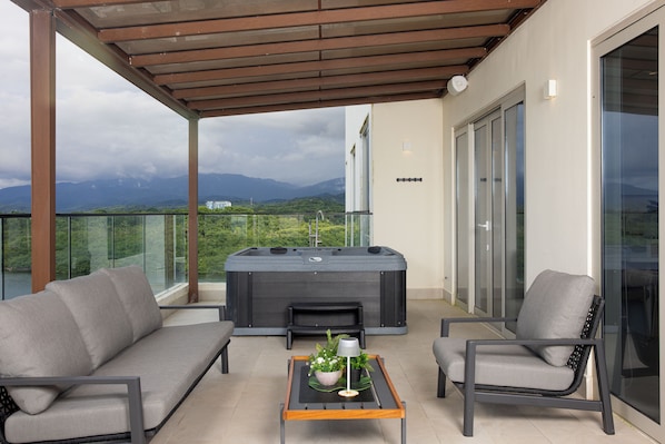 A balcony with a hot tub, two sofas, and a table with a plant.