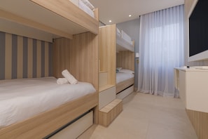 A modern hotel room with bunk beds, a desk, and a television.