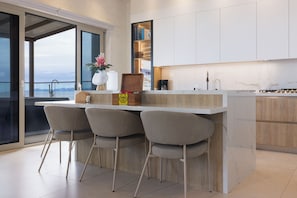 A modern kitchen with a bar area, large windows, and a view of the sea.