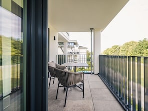 A balcony with a table and chairs, a view of neighboring buildings, and a metal railing. - Holiday Apartment With 1 Bedroom (Zingst)