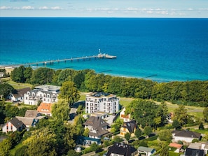 A coastal residential area with houses, a pier, and a clear view of the ocean. - Holiday Apartment With 1 Bedroom (Zingst)
