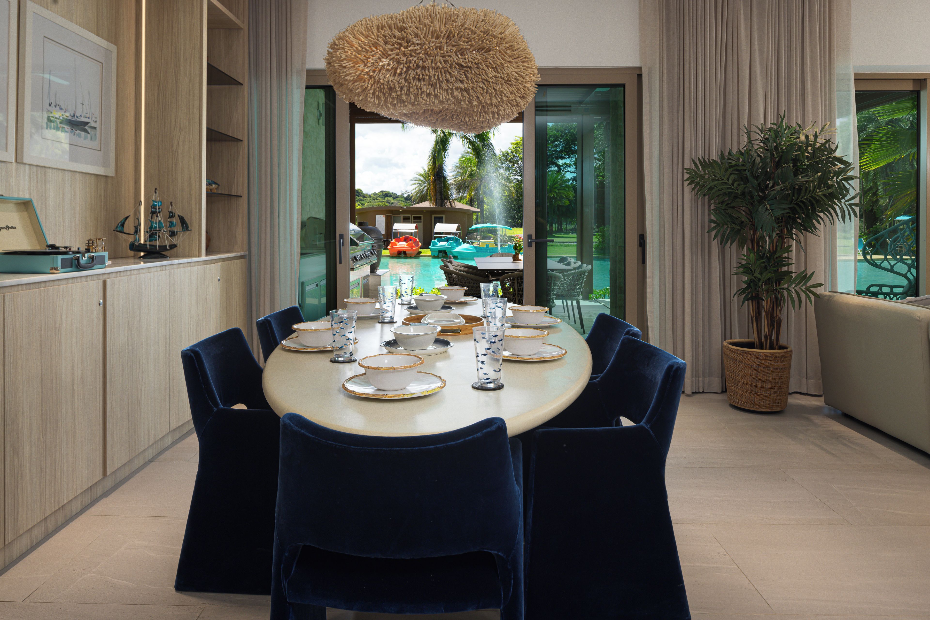 A dining area with a round table set for six, surrounded by dark blue chairs.
