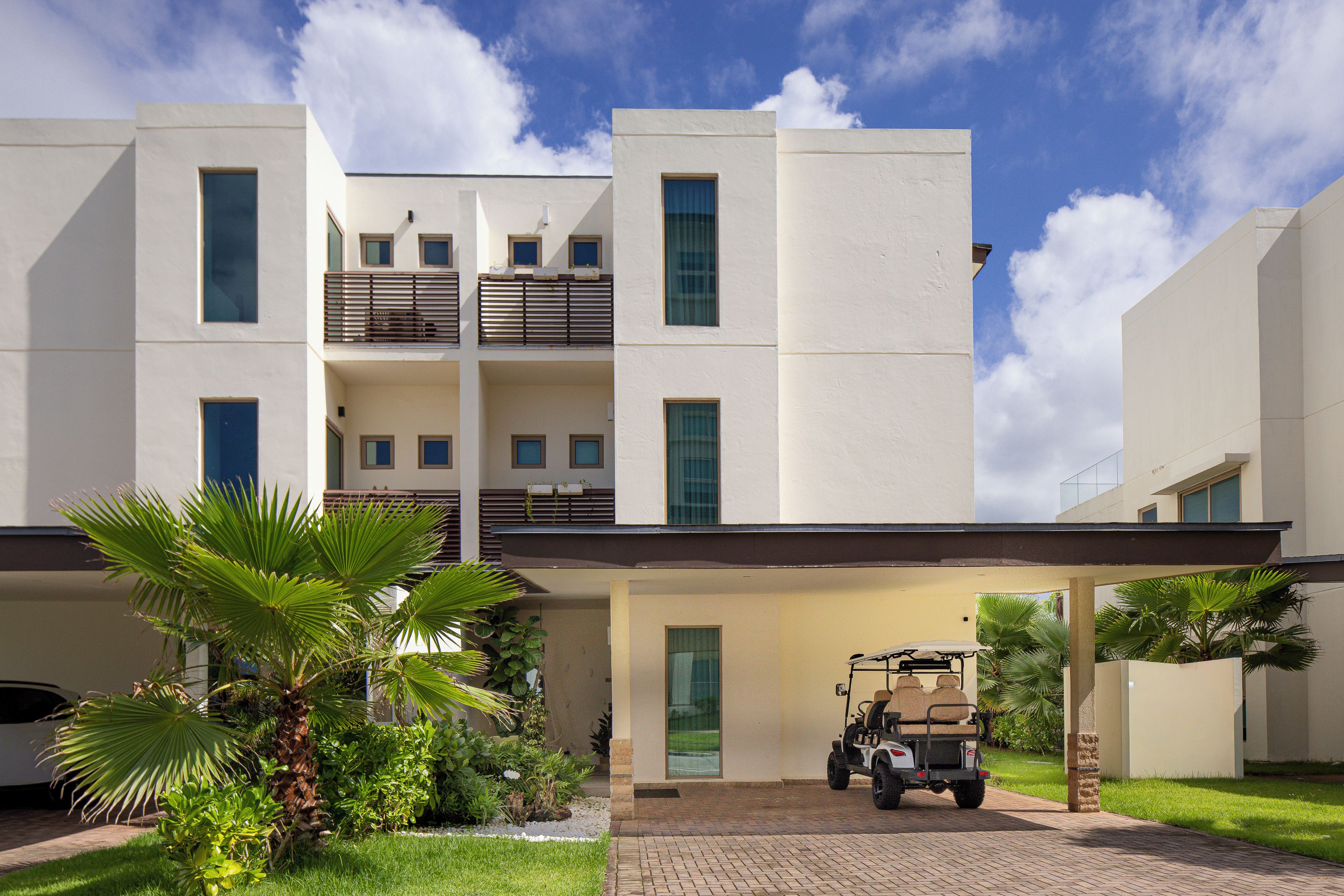 A modern multi-story building with a covered entrance and a golf cart parked outside.