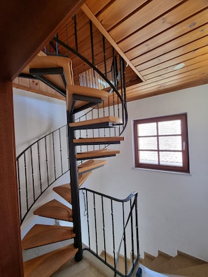 Eine Wendeltreppe mit Holzbodenstufen und schwarzen Geländern, die zu einer oberen Etage führt.