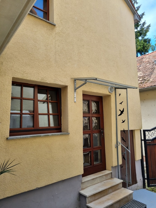 Ein Gebäude mit einer beige farbenen Fassade, einer Holztür und einem Fenster mit Metallrahmen.