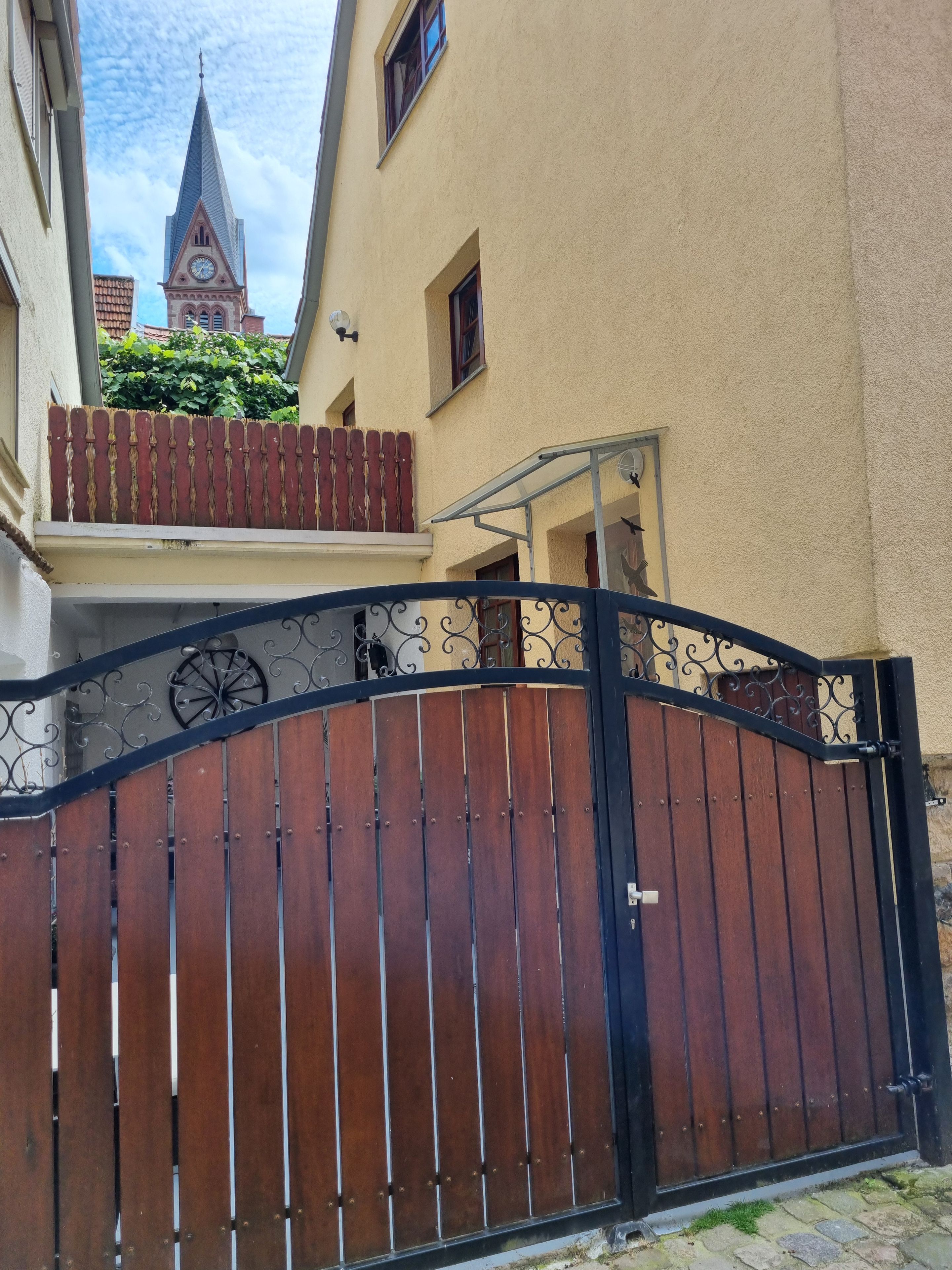 En lukket indgang med jerngitter og en balkon med rødt gelænder.
