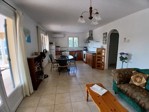 A living room with a sofa, a wooden table, and a dining area with chairs and a table. - Les Ecologies, friendly but private with space to enjoy the views (Cessenon-sur-Orb)