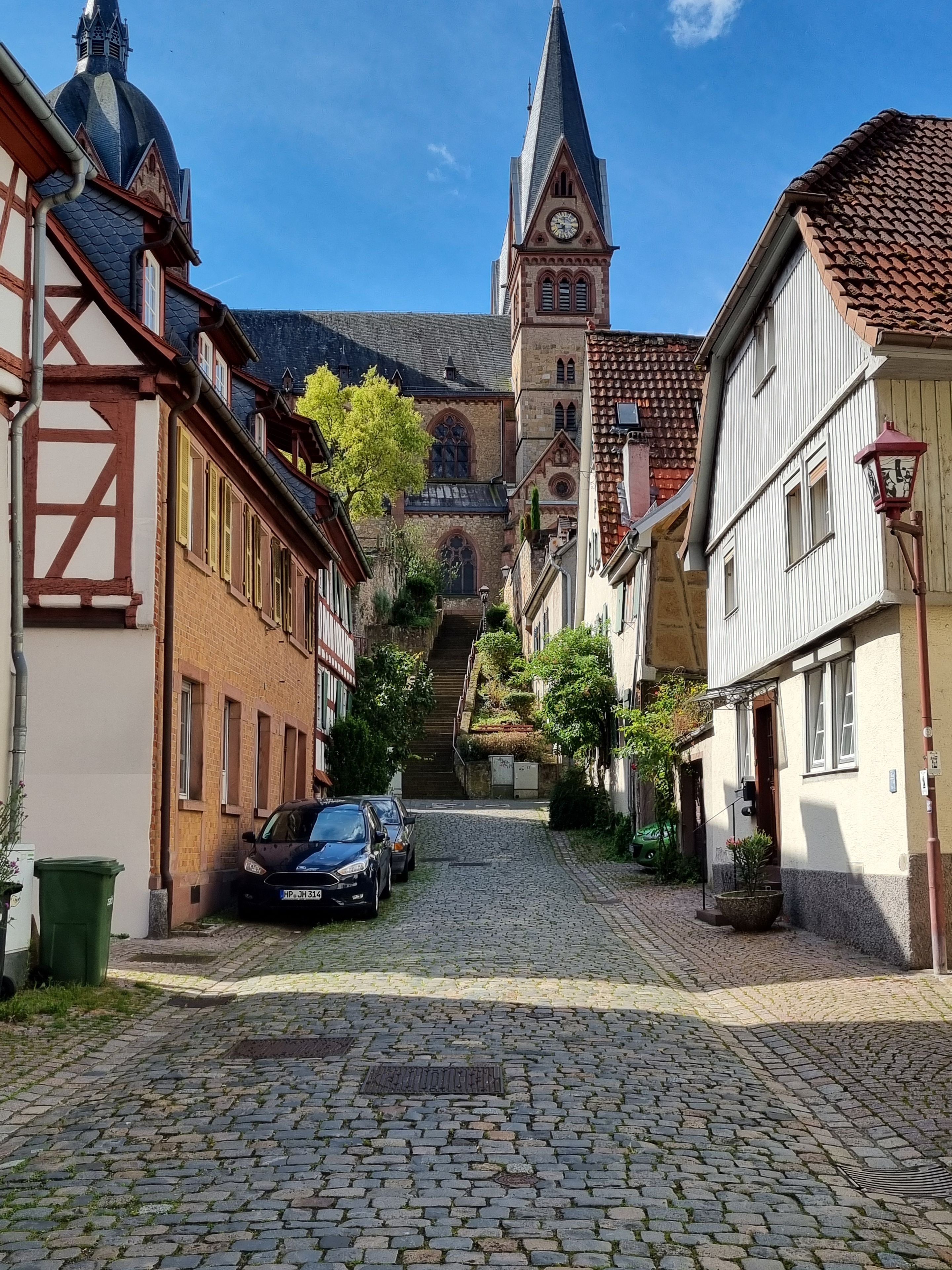 Eine Kopfsteinpflasterstraße führt zu einer Kirche mit einem Glockenturm.