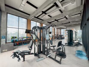 A gym with various exercise equipment, large windows, and a view of the city. - Modern Providencia Loft with Pool, Gym & Coworking (Guadalajara)