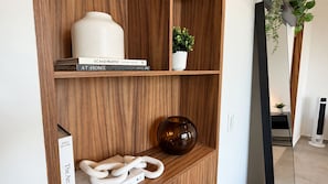 A wooden bookshelf with decorative items, a potted plant, and a white vase. - Modern Providencia Loft with Pool, Gym & Coworking (Guadalajara)