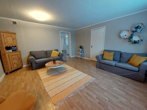 Un salon avec deux canapés, une table basse, un tapis et un meuble.