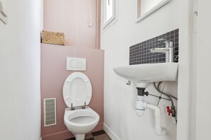 A bathroom with a toilet, a sink, and a window. - Lovely Flat near Notre-Dame & Le Marais (Paris)