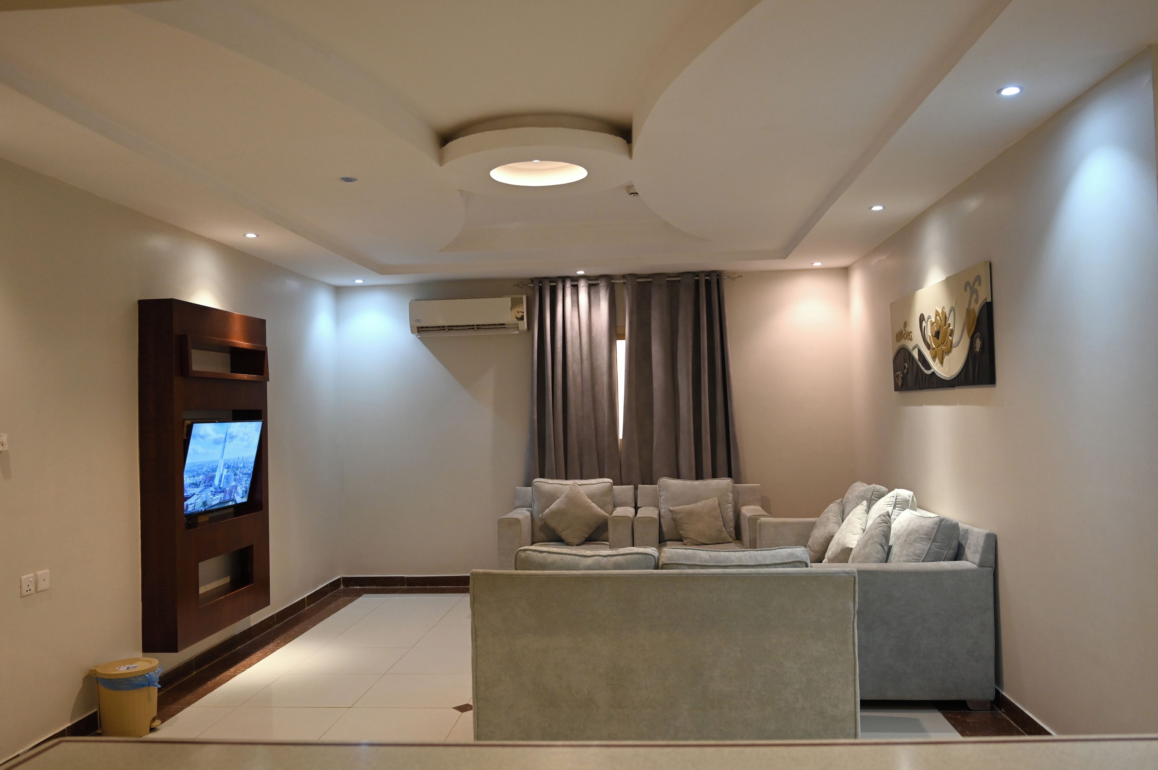 A modern living room with a flat-screen TV, a sofa, and a decorative wall piece.