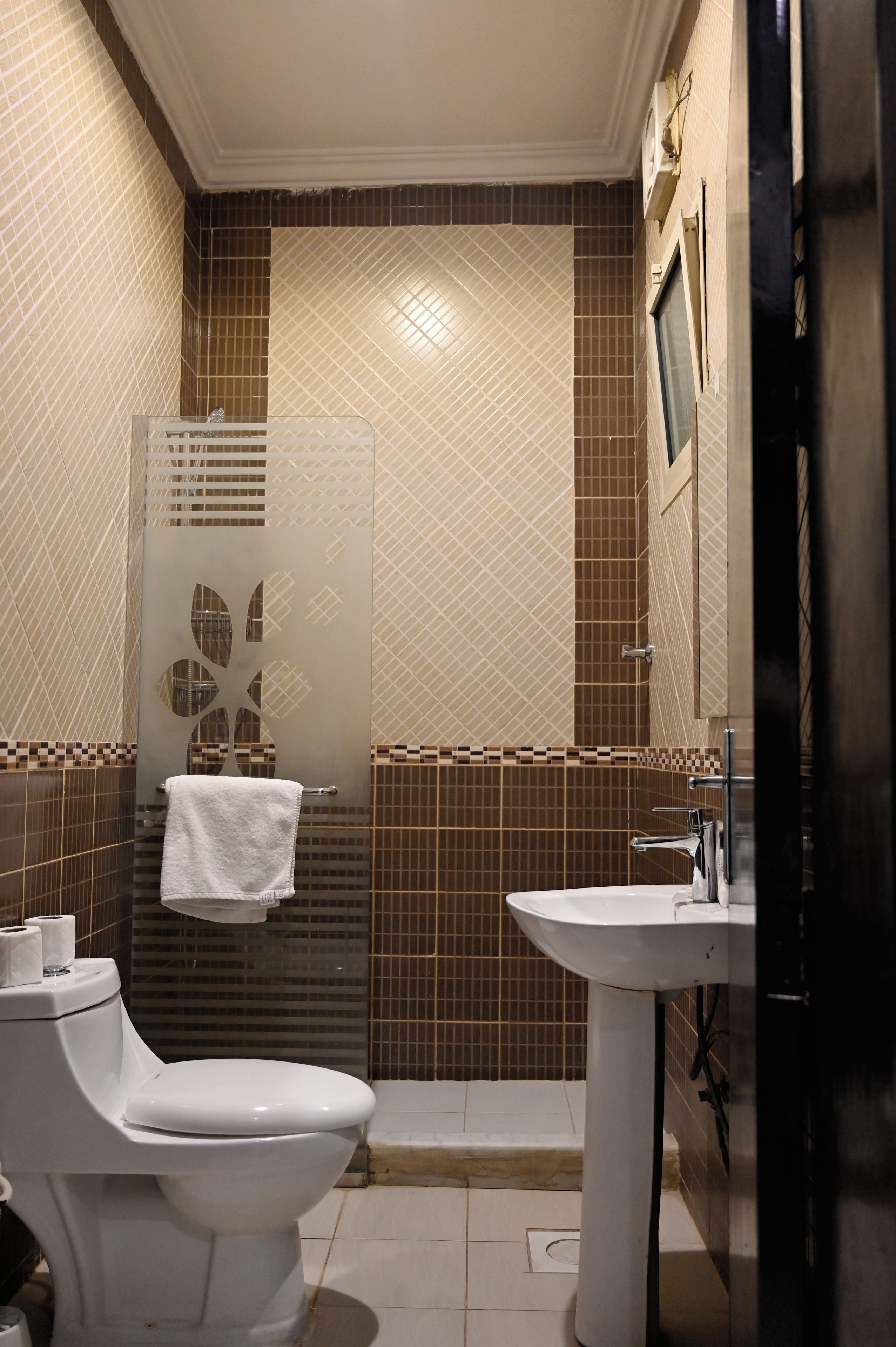 A bathroom with a toilet, sink, and shower area.