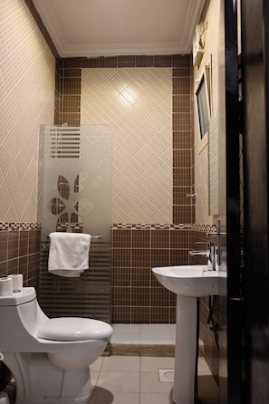 A bathroom with a toilet, sink, and shower area. - Quiet room 15 (riyadh)