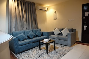 A living room with two sofas, a coffee table, a rug, and a door with a sign. - Quiet room 15 (riyadh)