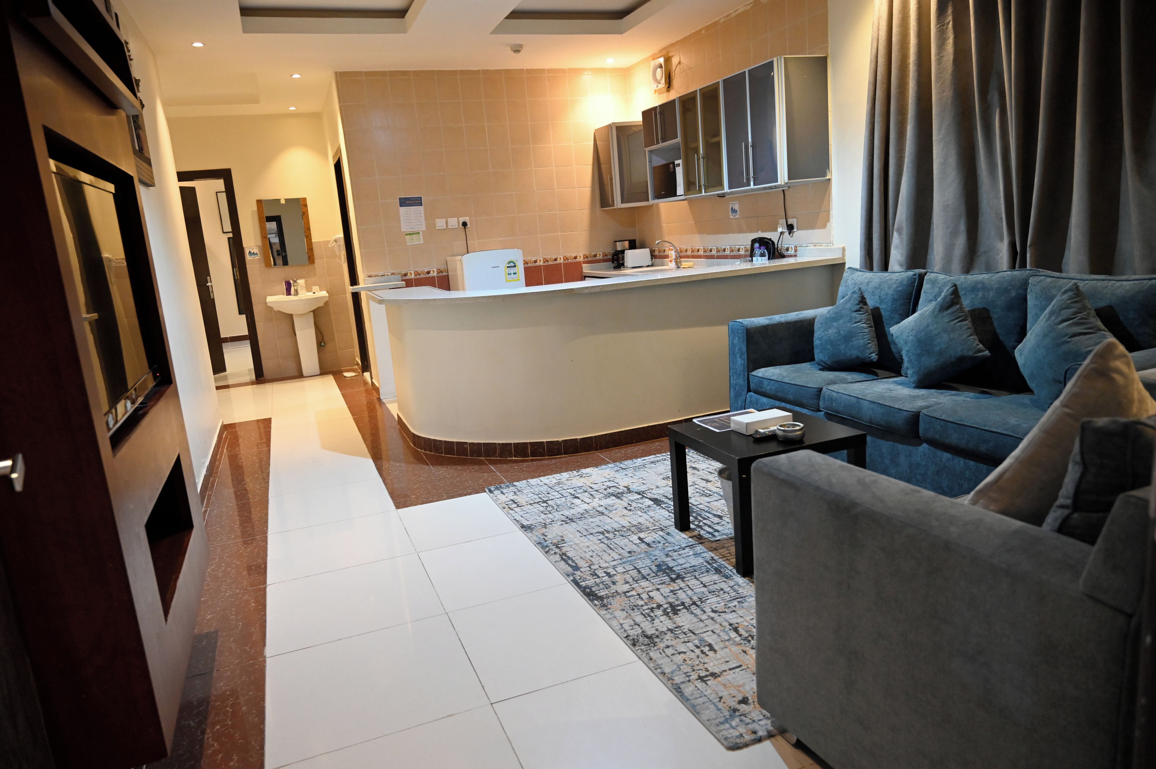 Une chambre d’hôtel moderne comprenant un coin salon, une kitchenette et une salle de bain.