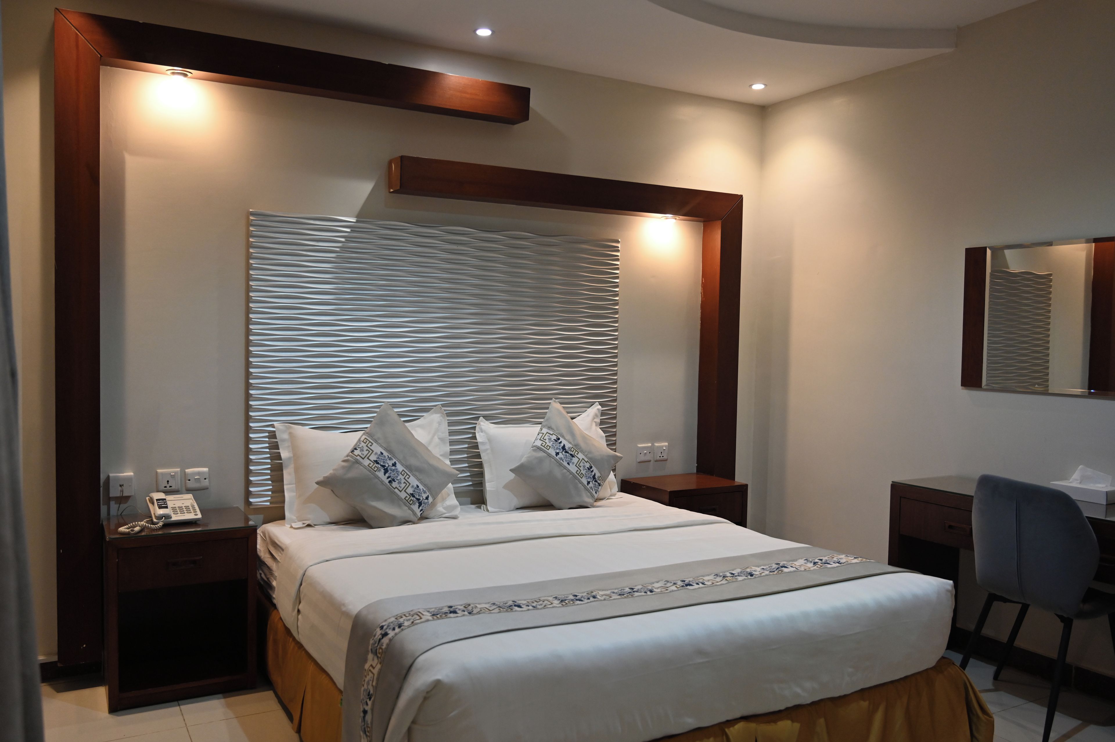 A hotel room with a large bed, bedside tables, a desk, and a chair.