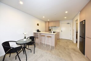 A compact kitchen with a dining area, a refrigerator, and a coffee machine. - Ground-Floor City Stay in Christchurch (Christchurch)