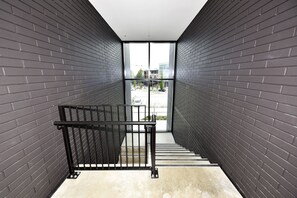 Una escalera moderna con barandillas negras que conduce a una puerta de cristal.