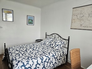 Une chambre à coucher avec un lit, une carte encadrée accrochée au mur et une petite table ronde.