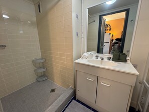 Ein Badezimmer mit Waschbecken, Spiegel und drei Regalen.