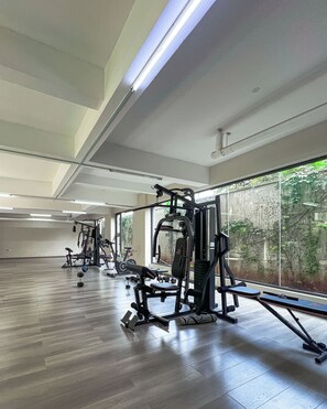 A gym with exercise equipment, large windows, and a wooden floor. - Homely • Stylish • Afro-Modern • Vibrant (Nairobi)