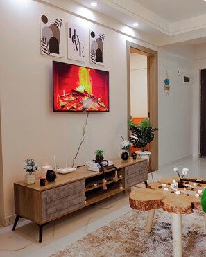 Ein modernes Wohnzimmer mit einem an der Wand befestigten Flachbildfernseher, einer Holz-Unterhaltungseinheit, einem runden Couchtisch und einem großen Spiegel.