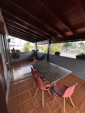An outdoor patio with a table and chairs, a fan, and potted plants. - Alessandra Ribeiro Squaiella (Caraguatatuba)