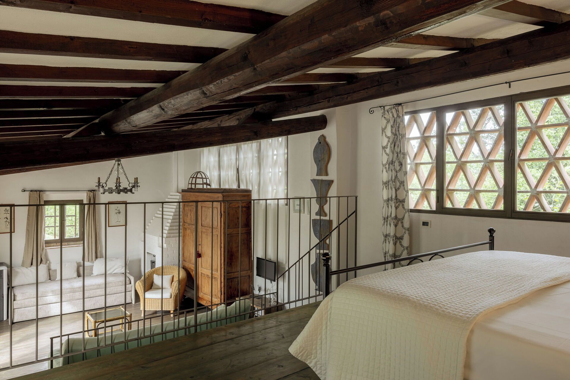 Ein Schlafzimmer mit einem Bett, einer Holztreppe, einem Holzkasten und einem Fenster mit Gittermuster.