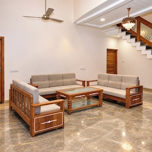 A modern living room with a sofa set, coffee table, and wooden side tables. - StayGuru Kutch Shahi Haveli (Bhuj)