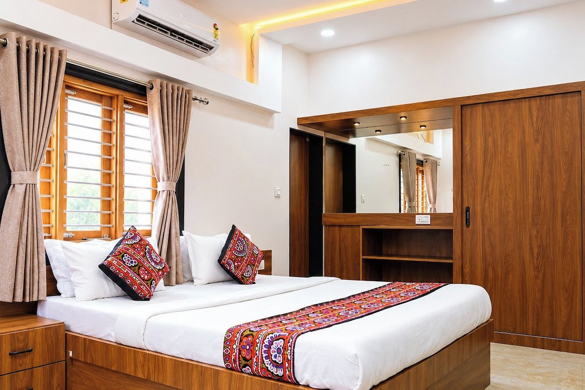 A bedroom with a bed, curtains, a ceiling fan, an air conditioning unit, and a wardrobe.