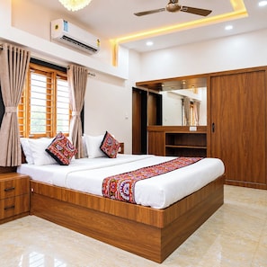 A bedroom with a bed, curtains, a ceiling fan, an air conditioning unit, and a wardrobe. - StayGuru Kutch Shahi Haveli (Bhuj)