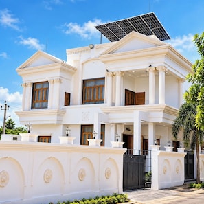 A two-story building with a symmetrical facade, large windows, and a solar panel on the roof. - StayGuru Kutch Shahi Haveli (Bhuj)